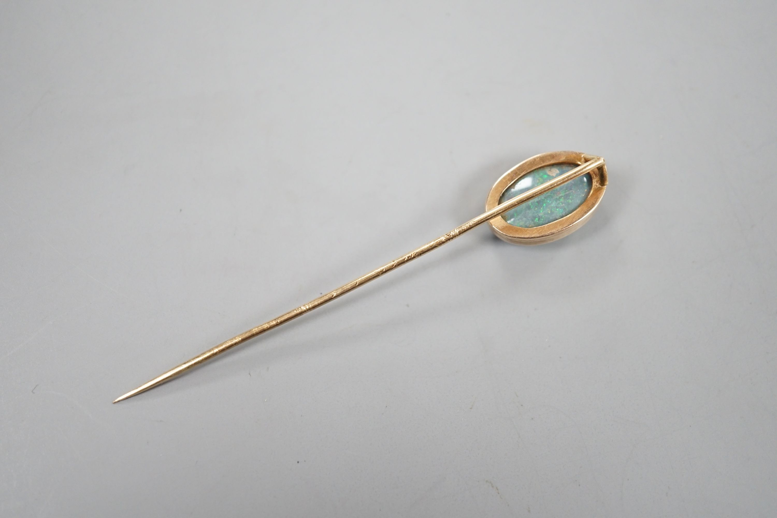 An Edwardian yellow metal and oval black opal set stick pin, 67mm, gross 2.7 grams